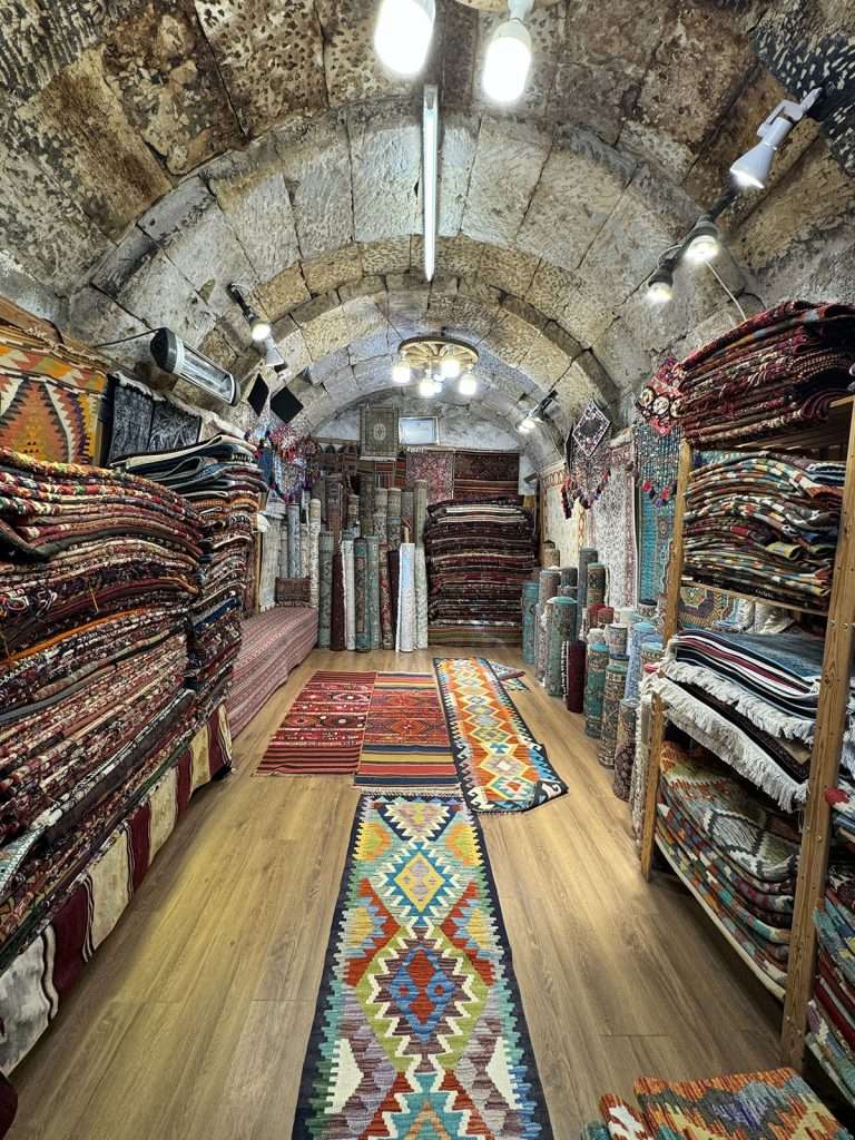 carpet shopping in Cappadocia with stacks of carpet in a small shop with a wooden floor